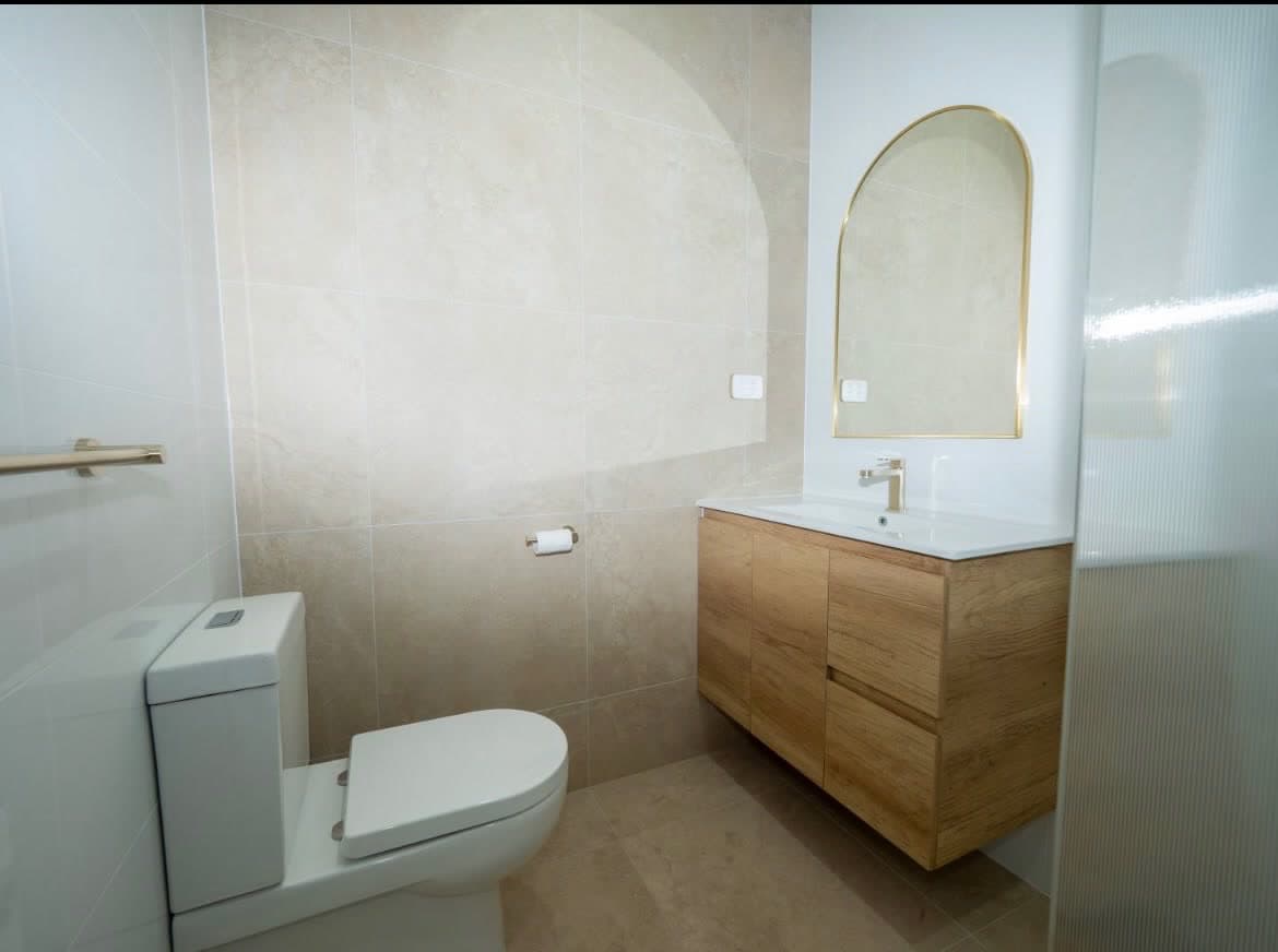 Renovated bathroom with an arched niche and timber vanity