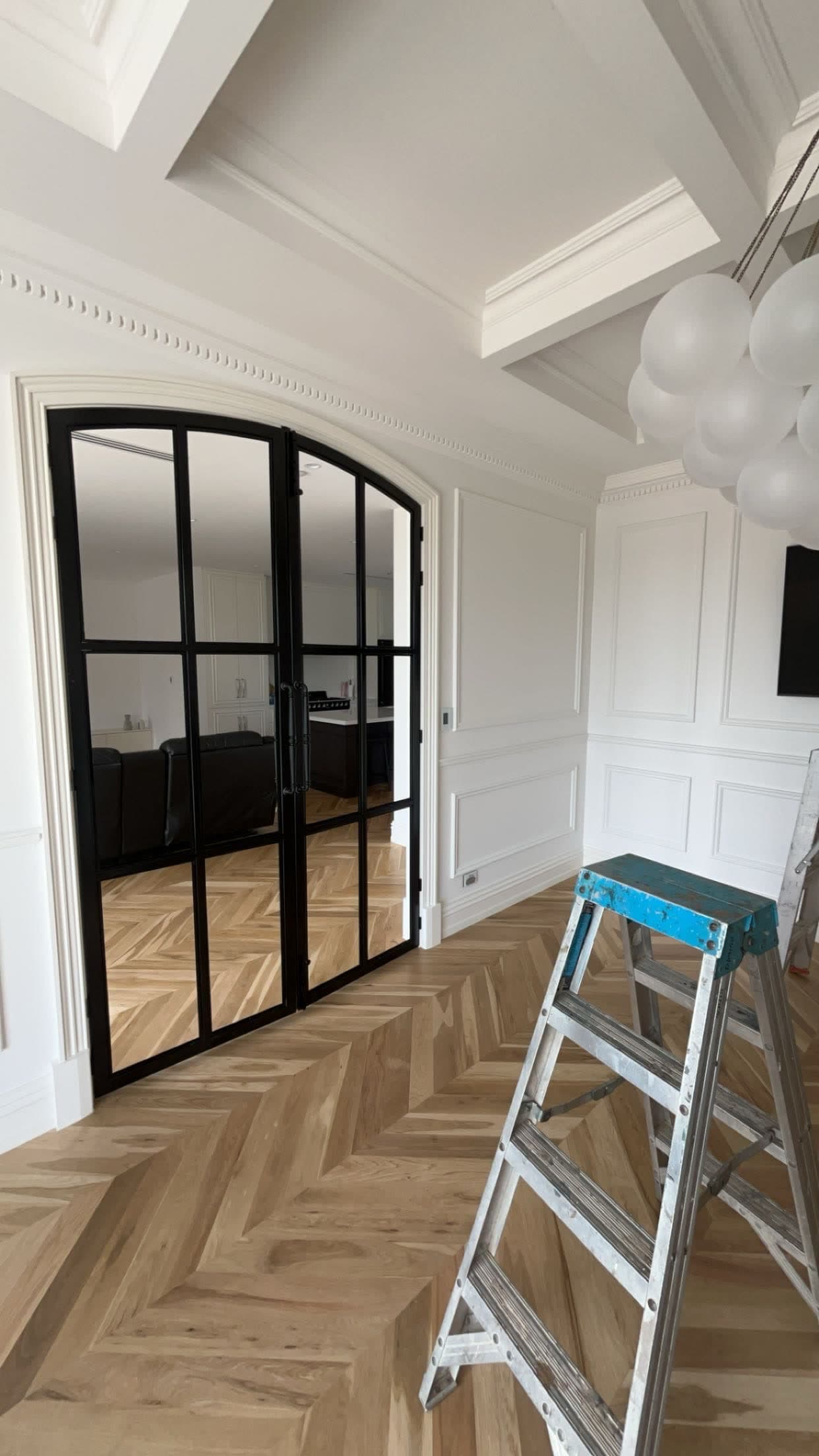 Black arched steel window and herringbone timber flooring at second fix stage