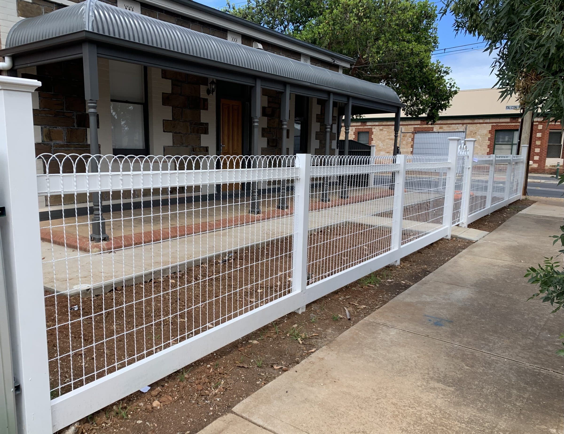 White heritage-style picket and wire fence along a stone verandah home
